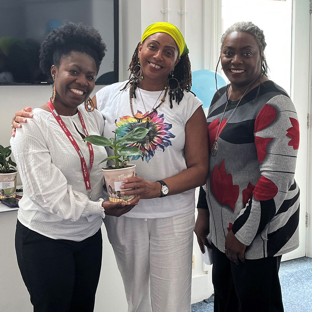 Three carers standing, one with rainbow coloured sunflower.